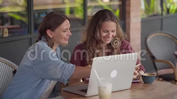 在户外咖啡馆和笔记本电脑一起工作的快乐女人视频的预览图