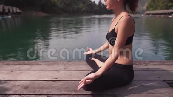 坐在湖边练习瑜伽的女人视频的预览图