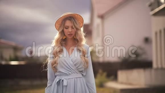 美丽的女人的画像一头金发穿着蓝色长裙走在外面微笑视频的预览图