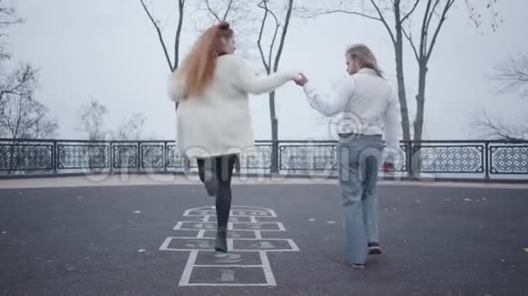 年轻的白种人穿着优雅的衣服牵着女朋友手她跳着画在上面的跳跳游戏视频的预览图