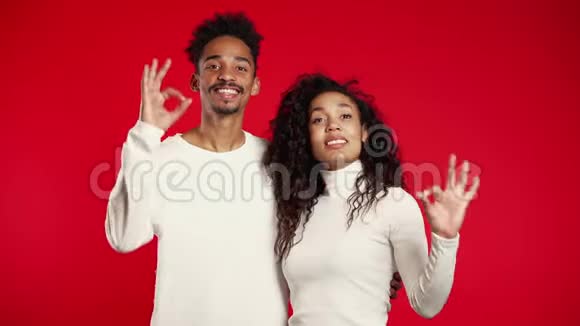 年轻的非洲夫妇在红色背景上做了OK标志赢家成功视频的预览图