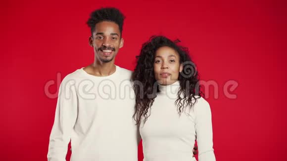 年轻的非裔美国夫妇在红色背景上竖起大拇指赢家视频的预览图