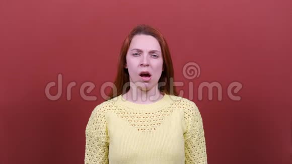 一个年轻的女人在镜头前打哈欠红色背景人真诚的情感生活方式的观念视频的预览图