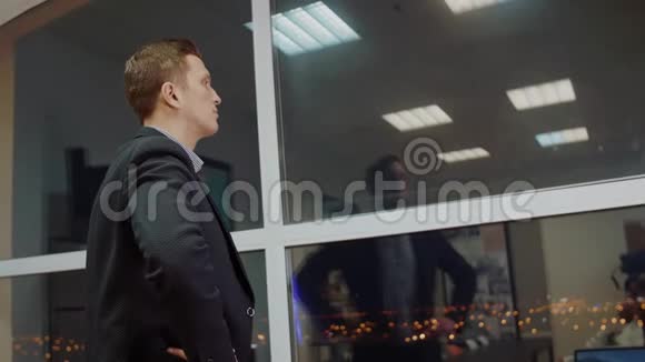 穿着公司服装的男性企业家在现代企业中等待商业伙伴时向窗外眺望视频的预览图