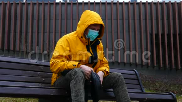 戴着医用口罩的病人坐在公园长椅上咳嗽得厉害视频的预览图