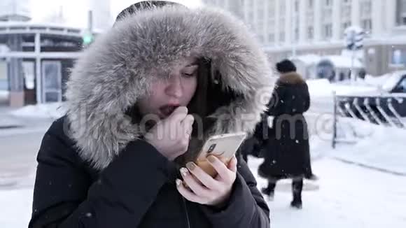 一个女人手里拿着一个电话想在寒冷的冬天打出租车视频的预览图
