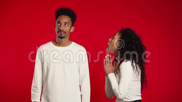 可爱的非洲年轻女人乞求她的男朋友或丈夫的红色背景视频的预览图