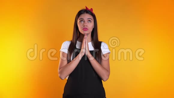 可爱的欧洲年轻女孩黑色整体祈祷黄色背景女人求人4k视频的预览图