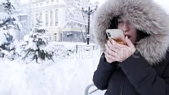 一个女人手里拿着一个电话想在寒冷的冬天打出租车视频的预览图