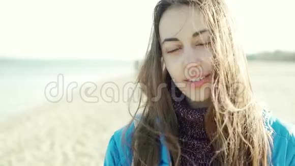 特写慢镜头肖像美丽的黑发女子户外沙滩风吹毛视频的预览图
