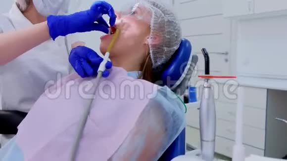 牙医在超声波清洗过程中用棉塞擦拭女性客户的牙齿视频的预览图