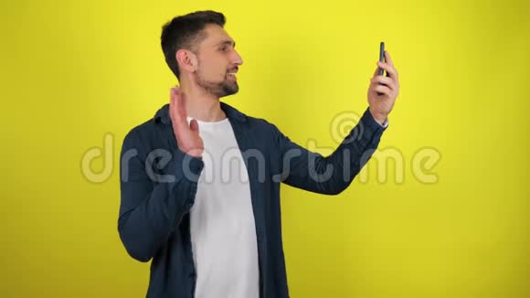 一位穿着蓝色衬衫和白色T恤的年轻博主正在智能手机上广播视频的预览图