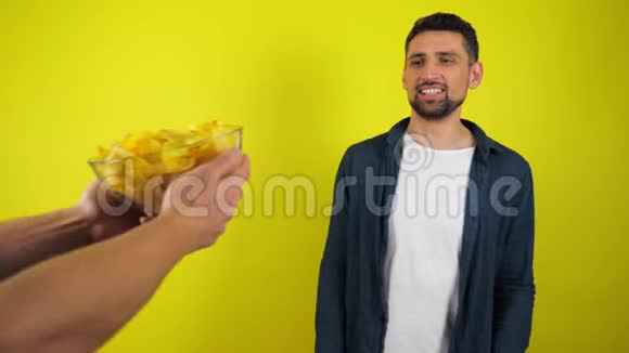 一个穿着蓝衬衫和白T恤的年轻人拒绝了一个装有薯条和垃圾食品的玻璃盘子视频的预览图