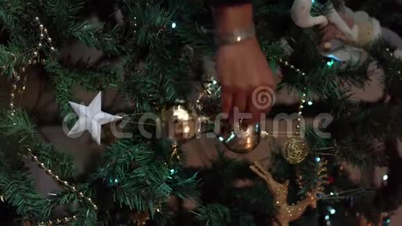 特写一个女人手在圣诞树上挂球的镜头圣诞装饰视频的预览图