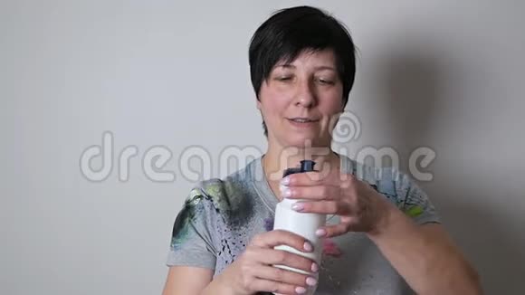 女人在拿着水瓶的年龄喝水微笑健身妇女在锻炼后休息视频的预览图
