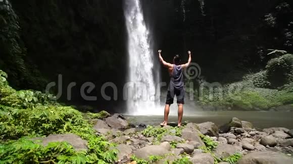 令人惊叹的Nungnung瀑布巴厘岛慢动作录像热带植物前景的流动相机视频的预览图