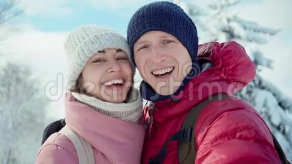 阳光明媚的冬日一对幸福微笑的年轻夫妇在白雪皑皑的冬季公园散步男人和女人很可爱视频的预览图