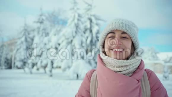 慢镜头特写照片穿着粉色大衣的开朗微笑的女人在阳光下的雪地公园里堆雪视频的预览图