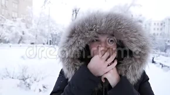 冬天的女孩吹在她的手上寒冷的天气雪霜冻冻僵少女在冬季公园散步视频的预览图