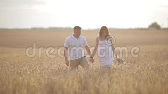一对相爱的夫妇走在金色黑麦的田野里视频的预览图