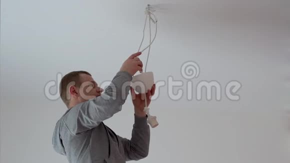 修和家装一个人从天花板上把灯挂在房间里视频的预览图