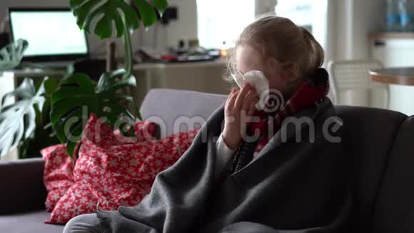 冷白种人女孩在家一个穿着围巾格子花格子的生病孩子在公寓沙发上的肖像那个女学生视频的预览图