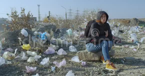一个女孩坐在一个被塑料袋污染的地方地球污染的规模令人印象深刻视频的预览图