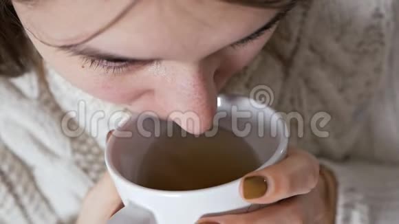 不健康的女孩拿着一杯热茶那个不幸的生病的年轻女子感冒了冻僵了对自己进行了治疗视频的预览图
