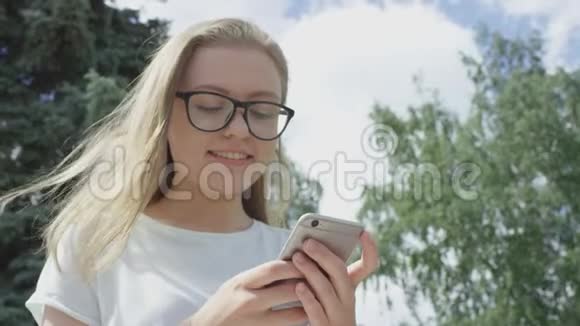 戴着眼镜的漂亮金发年轻女性对她的智能手机屏幕感到困惑和惊讶视频的预览图