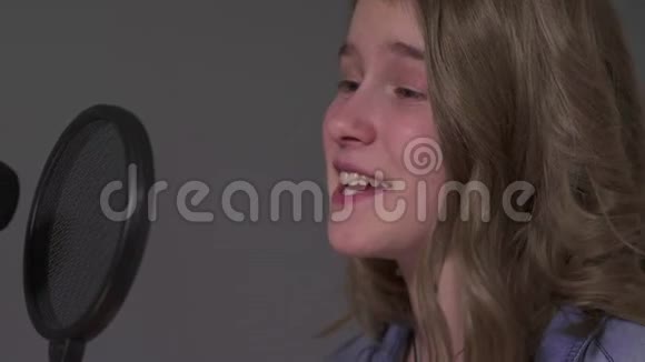 白人少年女孩用挂着的麦克风和设备唱一首歌视频的预览图