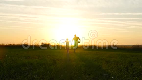 幸福的一家人父子在夕阳的映衬下穿过绿茵场视频的预览图