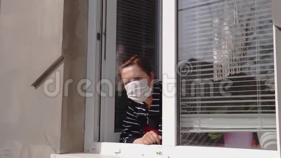 一个戴着医用口罩的女人望着窗外视频的预览图