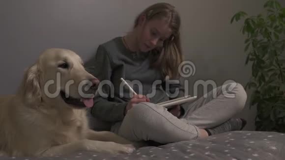 女孩坐在一个房间的床上和她的狗在画画视频的预览图