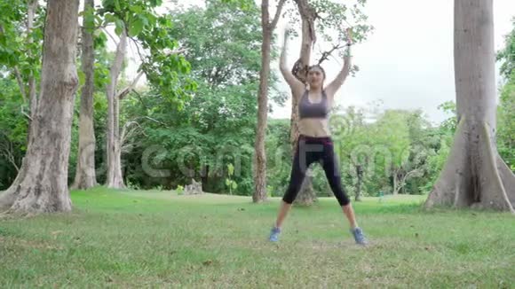 年轻健康的亚洲女性在户外自然公园晨练时伸展身体身体健康视频的预览图