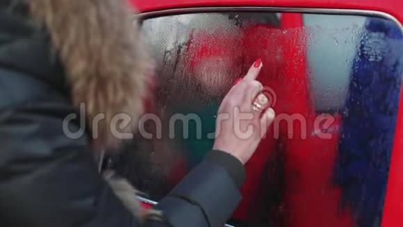 在冰车车窗镜头上特写女性手画心形视频的预览图