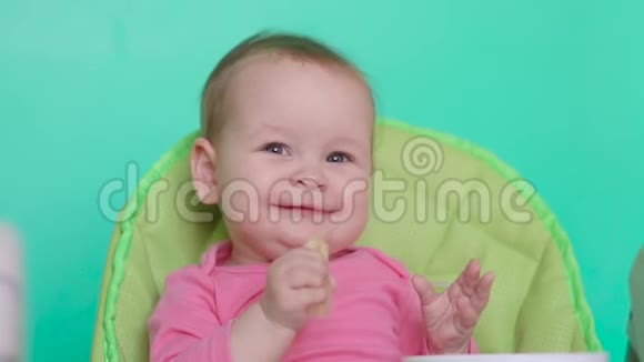 小女孩坐在厨房儿童椅子上吃着一个多汁的梨视频的预览图