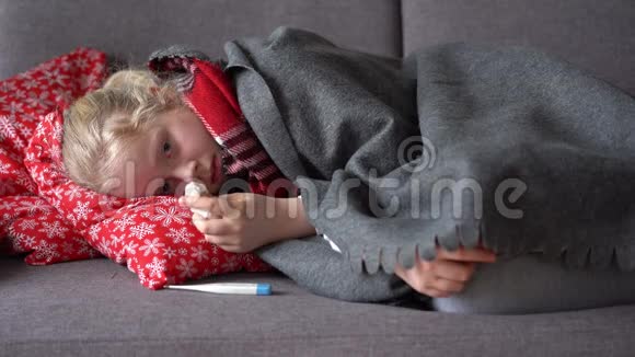冷白种人女孩在家公寓沙发上一个戴着围巾和格子的生病孩子的画像视频的预览图
