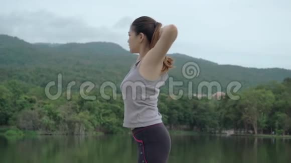 年轻健康的亚洲女人在户外自然公园晨练时伸展身体视频的预览图