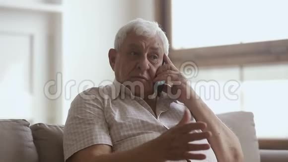 快乐的老人拿着手机在家打电话视频的预览图