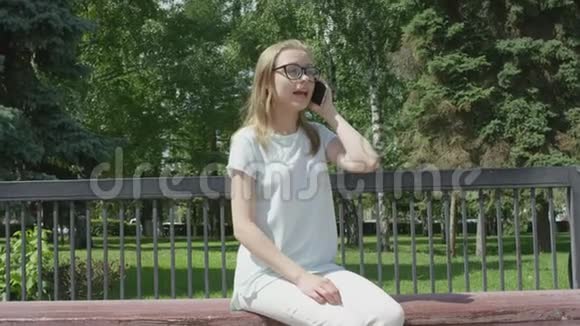 在公园的木座上休息时一位非常有魅力的年轻女性通过电话讨论重要的事情视频的预览图