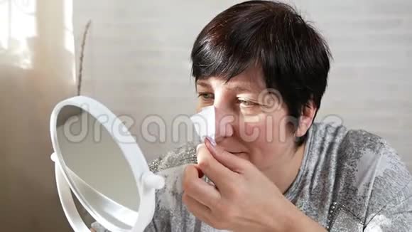 一位老年妇女借助清洁贴纸去除鼻子皮肤上的黑点鼻腔清洗条视频的预览图