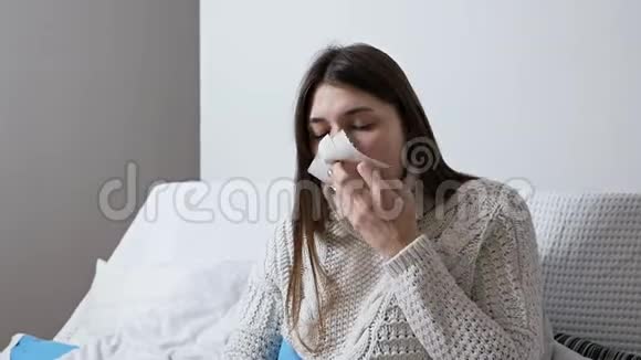 保健和医疗理念年轻生病的女人晚上在家里沙发上打喷嚏女孩流鼻涕抱着视频的预览图