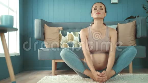 漂亮的孕妇在地板上做瑜伽准妈妈正在锻炼视频的预览图