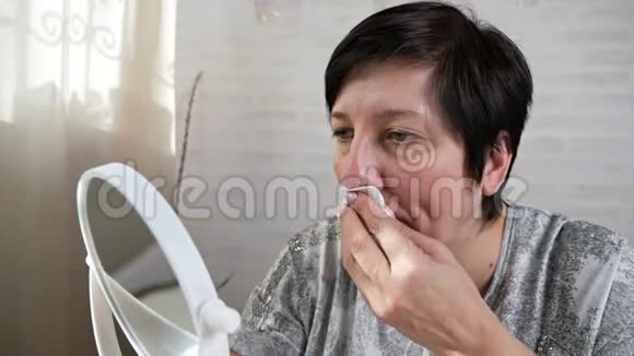 一位老年妇女借助清洁贴纸去除鼻子皮肤上的黑点鼻腔清洗条视频的预览图