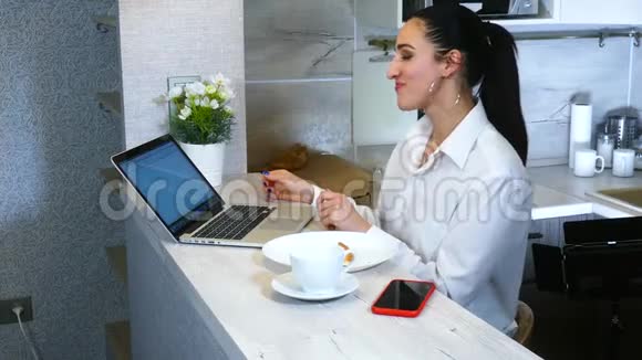 快乐的西班牙女人在厨房用笔记本电脑完成笑与同事交流视频的预览图
