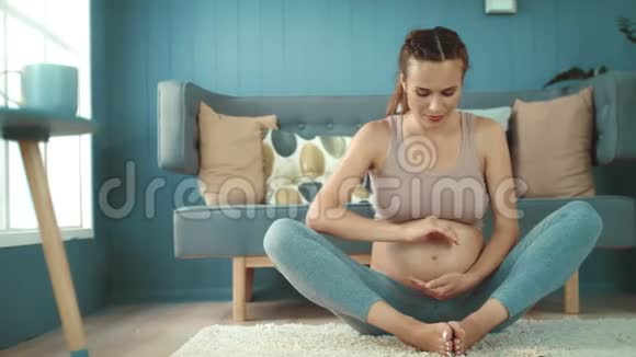 特写微笑的孕妇在家里的地板上拍照视频的预览图