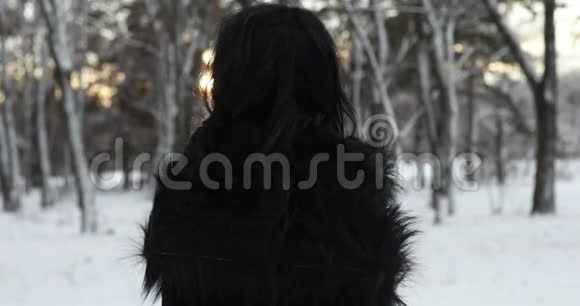 Cosplayer描绘了一个女人在日落时分在雪林中的女巫形象视频的预览图