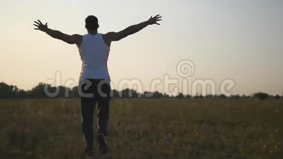举起双手在田野里奔跑享受自由的年轻人夏天在草地上奔跑的无忧无虑的家伙视频的预览图