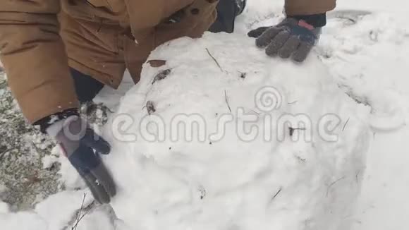 男孩为雪人滚一个大雪球视频的预览图