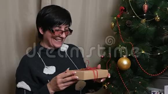 在圣诞树上有圣诞礼物的老年妇女视频的预览图